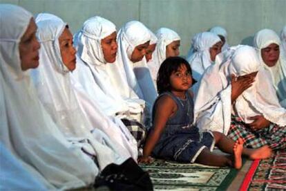 Una niña, sentada junto a su madre y otras mujeres durante un acto en recuerdo de las víctimas del maremoto en Landung, Banda Aceh.