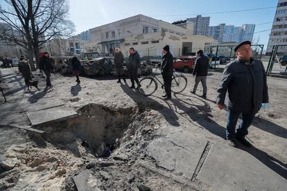 Personas observan el cráter de un proyectil después de un bombardeo en una zona residencial de Kiev, Ucrania, en febrero de 2022.