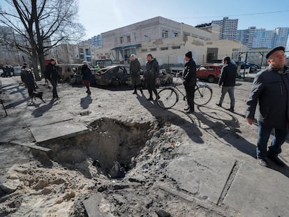 Personas observan el cráter de un proyectil después de un bombardeo en una zona residencial de Kiev, Ucrania, en febrero de 2022.
