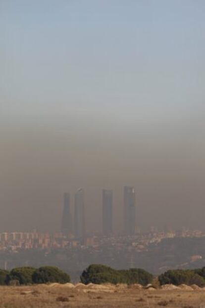 Las modernas torres de Madrid permanecen sumergidas en una espesa capa de bruma y contaminación, ayer.