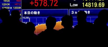 Peatones se dentienen ante una pantalla electr&oacute;nica con los datos del cierre de la Bolsa de Tokio (Jap&oacute;n). 