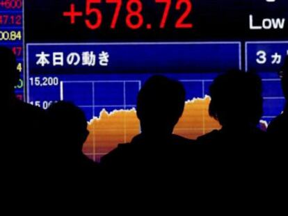 Peatones se dentienen ante una pantalla electr&oacute;nica con los datos del cierre de la Bolsa de Tokio (Jap&oacute;n). 