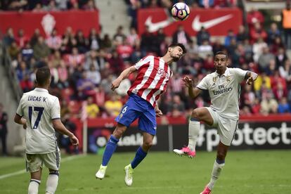 Sergio Álvarez (c), del Sporting de Gijón, golpea el balón de cabeza ante la presencia de Danilo.