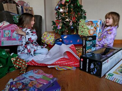 Dos niñas abren sus regalos, durante la mañana de un día de Reyes, en Madrid.