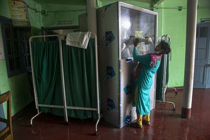 Un sanitario realiza una prueba PCR desde una cabina en Gauhati (India). 