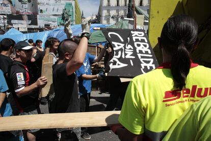 Varias personas contribuyen en el desmontaje de las tiendas y puestos que durante 25 días han permanecido instalados en la Puerta del Sol de la capital.