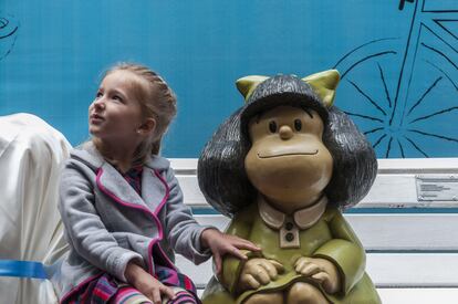 Luisa, la hija del escultor Pablo Irrgang, se sienta junto a la escultura de Mafalda de su padre durante la inauguración de dos esculturas más de los personajes de Quino, el 29 de septiembre de 2014 en Buenos Aires.