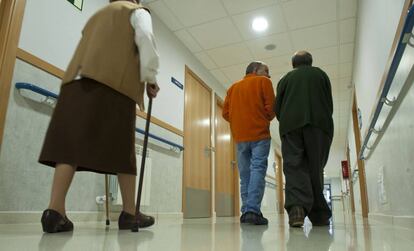 Dos mujeres, una con un andador, en un pasillo de la residencia de ancianos.