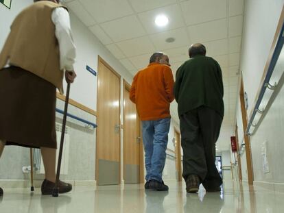 Dos mujeres, una con un andador, en un pasillo de la residencia de ancianos.