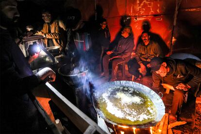 Un grupo de hombre usan linternas mientras cocinan en un campamento improvisado en Rafah, este viernes.  