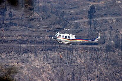 Un helicóptero sobrevuela una de las zonas arrasadas por las llamas en el municipio sevillano de El Madroño.