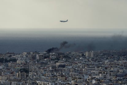 A Middle East Airlines airplane flies over Beirut as smoke rises from Dahiyeh, in Beirut, Lebanon, Tuesday, Oct. 1, 2024. (AP Photo/Bilal Hussein)