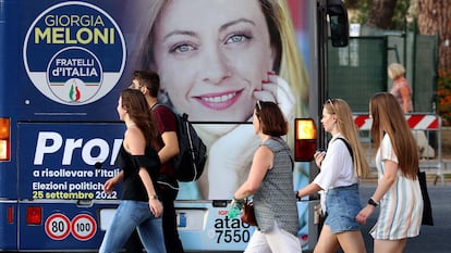 Un grupo de jóvenes, ante una publicidad electoral de Meloni, en Roma.