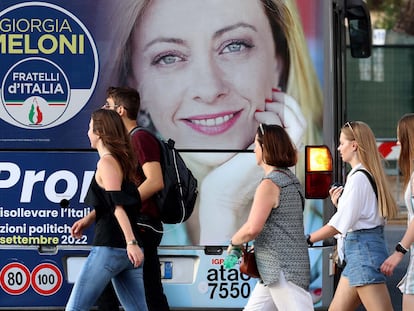 Un grupo de jóvenes, ante una publicidad electoral de Meloni, en Roma.