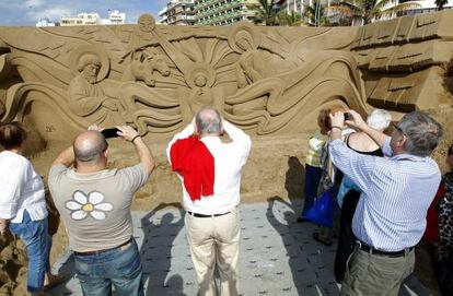 Varios turistas fotografían un belén de Arena en la playa de Las Canteras, en Las Palmas de Gran Canaria.