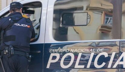 Un agente de la Policía Nacional junto a un vehículo del cuerpo.