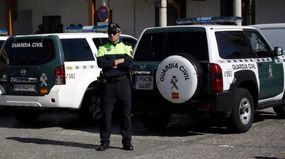 Agente de la Guardia Civil junto a dos vehículos del cuerpo.