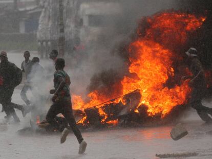 Un grupo de personas corre junto a una barricada en llamas durante la jornada de protestas en Harare.