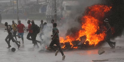 Un grupo de personas corre junto a una barricada en llamas durante la jornada de protestas en Harare.