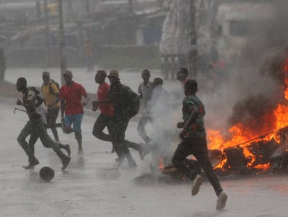 Un grupo de personas corre junto a una barricada en llamas durante la jornada de protestas en Harare.