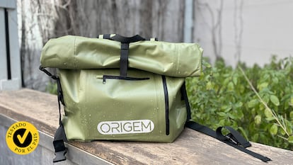 Mochila impermeable apoyada en un bordillo en la calle y mojada