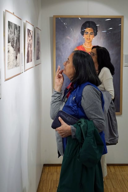Visitantes de la exposición ‘Ángeles, el equilibrio de Miguel Delibes’ y, al fondo, el óleo en el que retrató a la esposa del escritor el pintor García Benito.