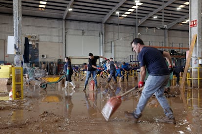 Trabajadores de una empresa de logística limpian el interior de una nave en el polígono industrial de Riba-roja de Túria.