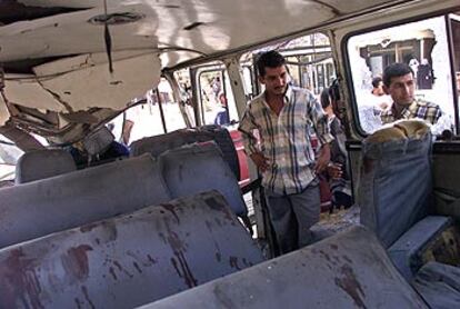 Dos iraquíes observan los asientos manchados de sangre del autobús alcanzado ayer por una bomba en Bagdad.