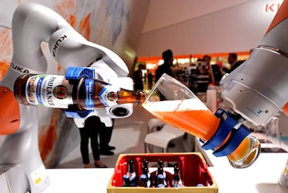 Un brazo de un robot llena un vaso de cerveza bávara en una feria en Hanover, en el stand de Kuka, una compañía aleman adquirida por otra china.