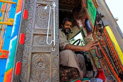 Un conductor sostiene la puerta de la cabina, de madera tallada, en Faisalabad.