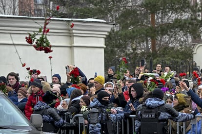 Asistentes que esperan en el exterior de la iglesia Utolí Mayá Pechali lanzan rosas y claveles al paso del coche fúnebre tras la misa, este viernes en Moscú.
