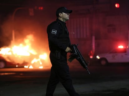 Un oficial camina junto a un vehículo incendiado por miembros del CJNG tras la detención de uno de sus líderes el pasado 9 de julio.