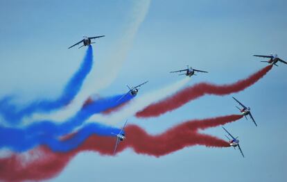 Aviones de la patrulla acrob&aacute;tica francesa dejan estelas de humo con los colores de la bandera nacional de su pa&iacute;s. 