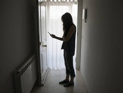 Una mujer utiliza su móvil en su domicilio.