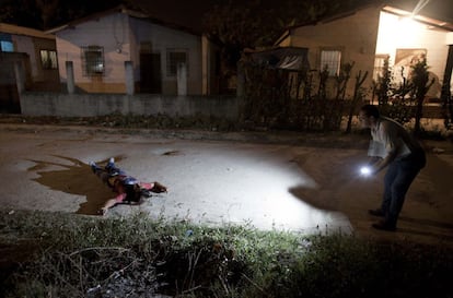 Un agente de la policía inspecciona el lugar donde ha sido asesinado un hombre en una calle de San Pedro de Sula, Honduras.