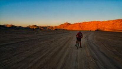 Un solitario ciclista cruza al amanecer un complicado tramo del desierto de Sudán.