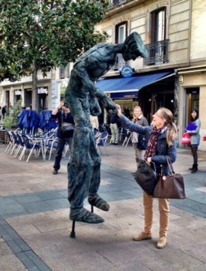 La réplica de la escultura 'El caminante' saluda a una mujer este lunes en Vitoria.