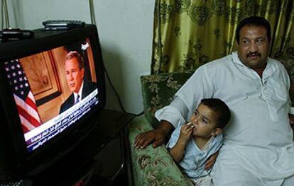 Un iraqu contempla, junto a su hijo, la entrevista con Bush en la cadena Al Arabiya el mircoles en Bagdad.