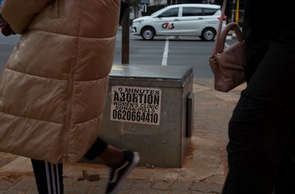 Women pass a sticker advertising abortion pills on a sidewalk in Johannesburg, Wednesday June 28, 2023.
