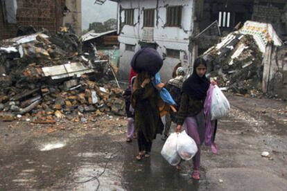 Un grupo de mujeres camina ante casas dañadas por el terremoto en la ciudad de Muzaffarabad, en Cachemira.