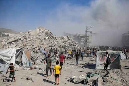 Palestinos caminan ante las ruinas de un edificio residencial en Gaza bombardeado por Israel.