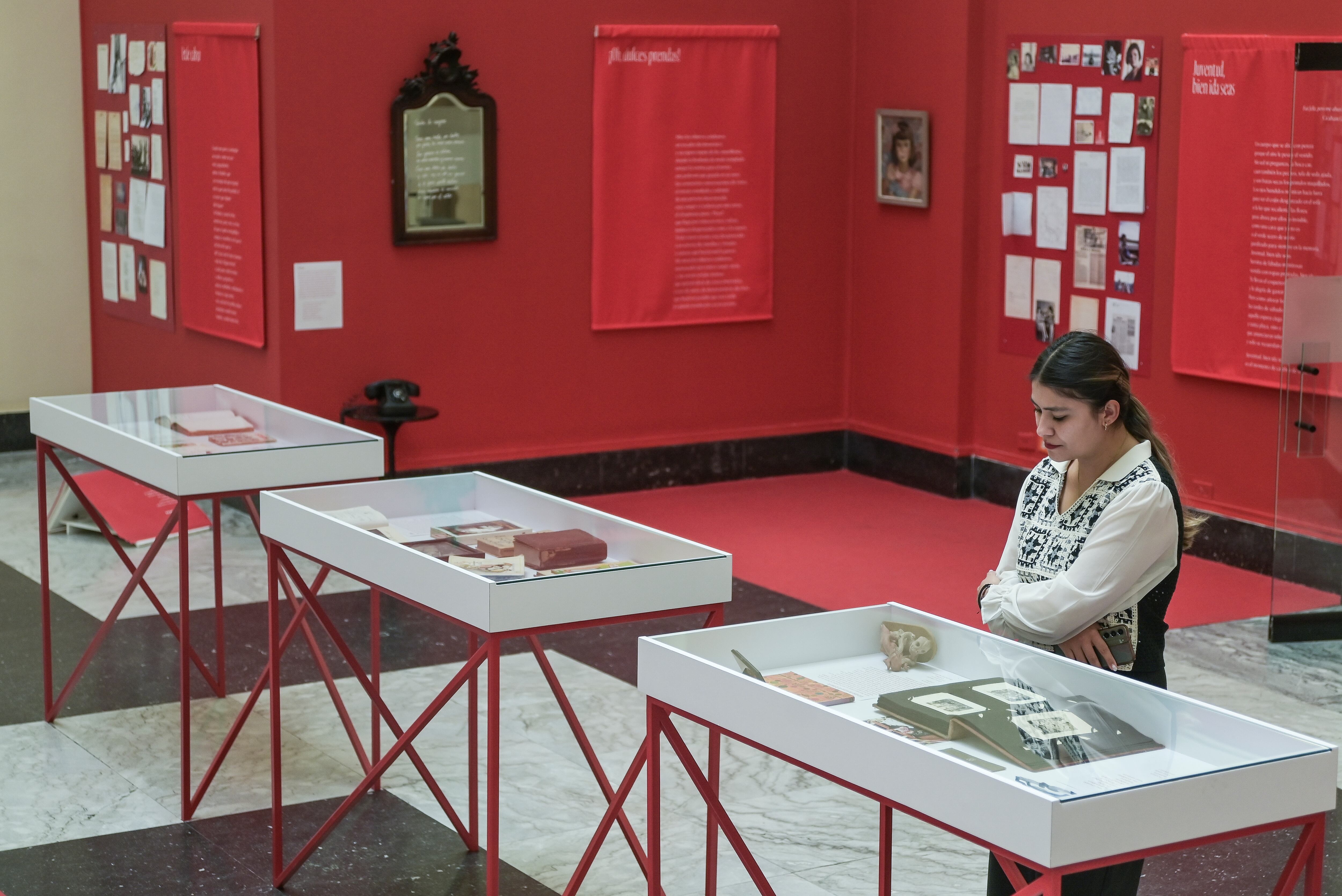 Una joven observa un álbum de fotografías que forma parte de la exposición de María Mercedes Carranza.