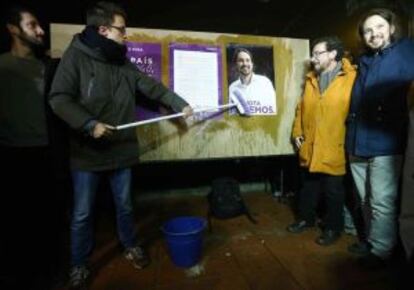 Errejón (i) durante la pega de carteles junto a Iglesias (d) y su padre.