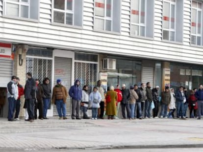Varias personas forman una larga cola ante una oficina del INEM.