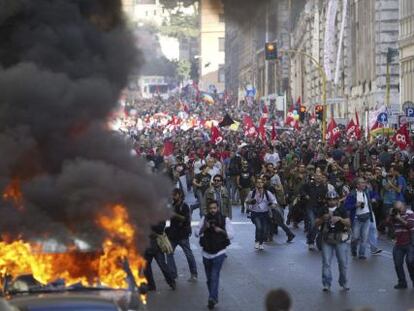 Varios vehículos arden hoy en el centro de Roma, durante la marcha de los indignados