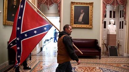 Un partidario del presidente Donald Trump lleva una bandera de batalla confederada en el segundo piso del Capitolio de los EE. UU. 