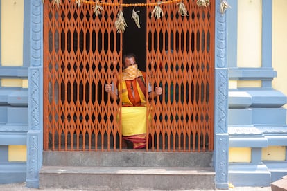Un monje hindú mira desde el interior de un templo en India.