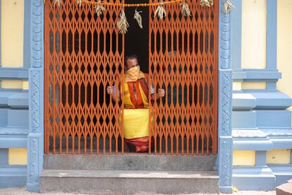 Un monje hindú mira desde el interior de un templo en India.