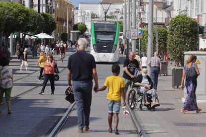El tranvía en pruebas pasa por la Calle Real de San Fernando, Cádiz compartiendo la avenida con el tránsito de peatones y coches autorizados, aún en su fase de pruebas en blanco