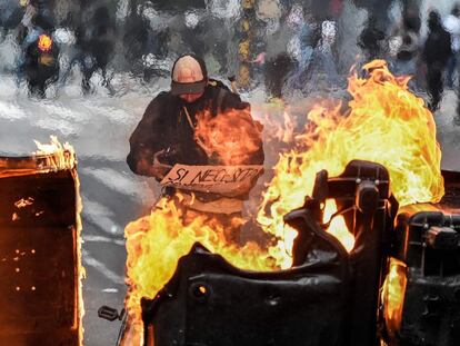 Un hombre toma unas fotos detrás de una barricada en llamas durante el quinto día consecutivo de protestas contra la brutalidad policial en Bogotá (Colombia).
